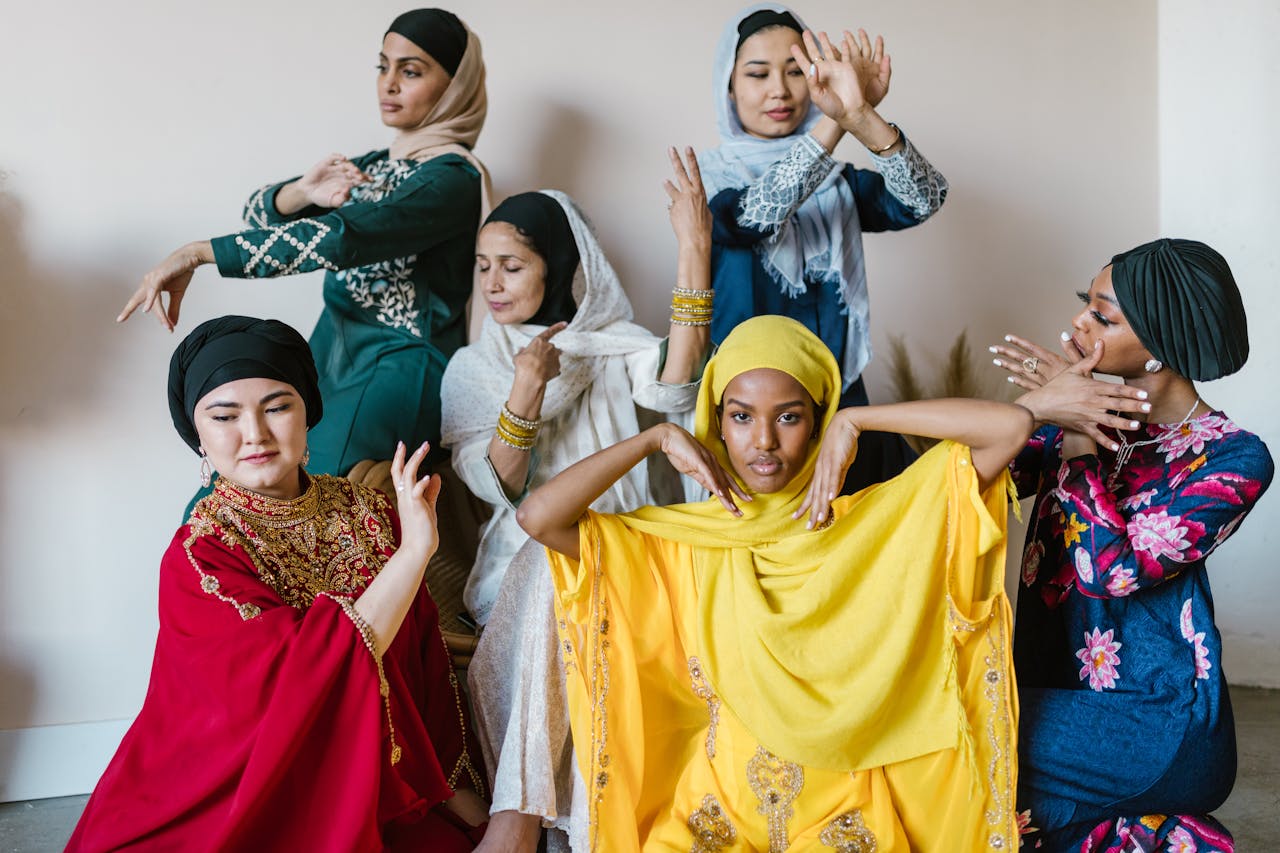 why-choose-us Group of multicultural women in traditional attire posing with expressive hand gestures indoors.