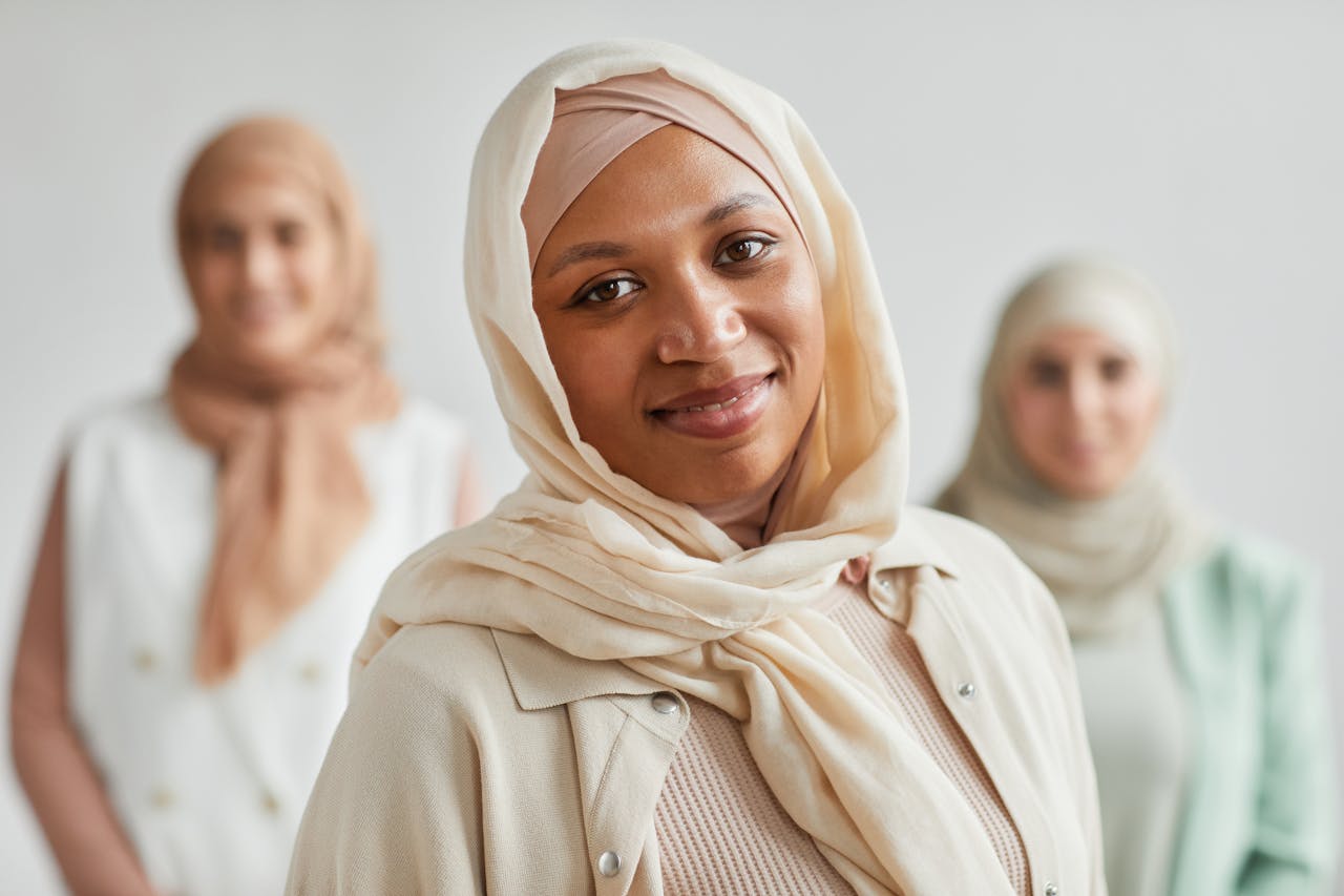 portfolio-01 Close-up of three diverse women in hijabs smiling with a soft background.