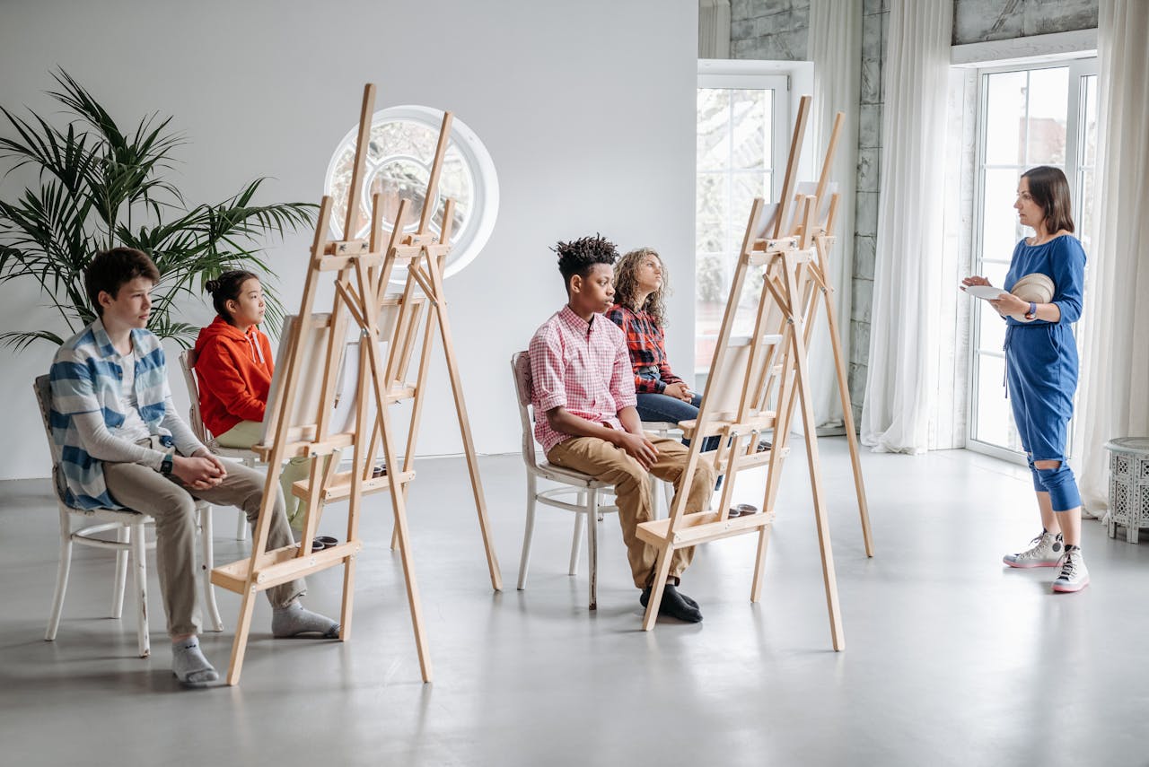 core-values Students in an art class with easels, guided by a teacher in a bright studio setting.