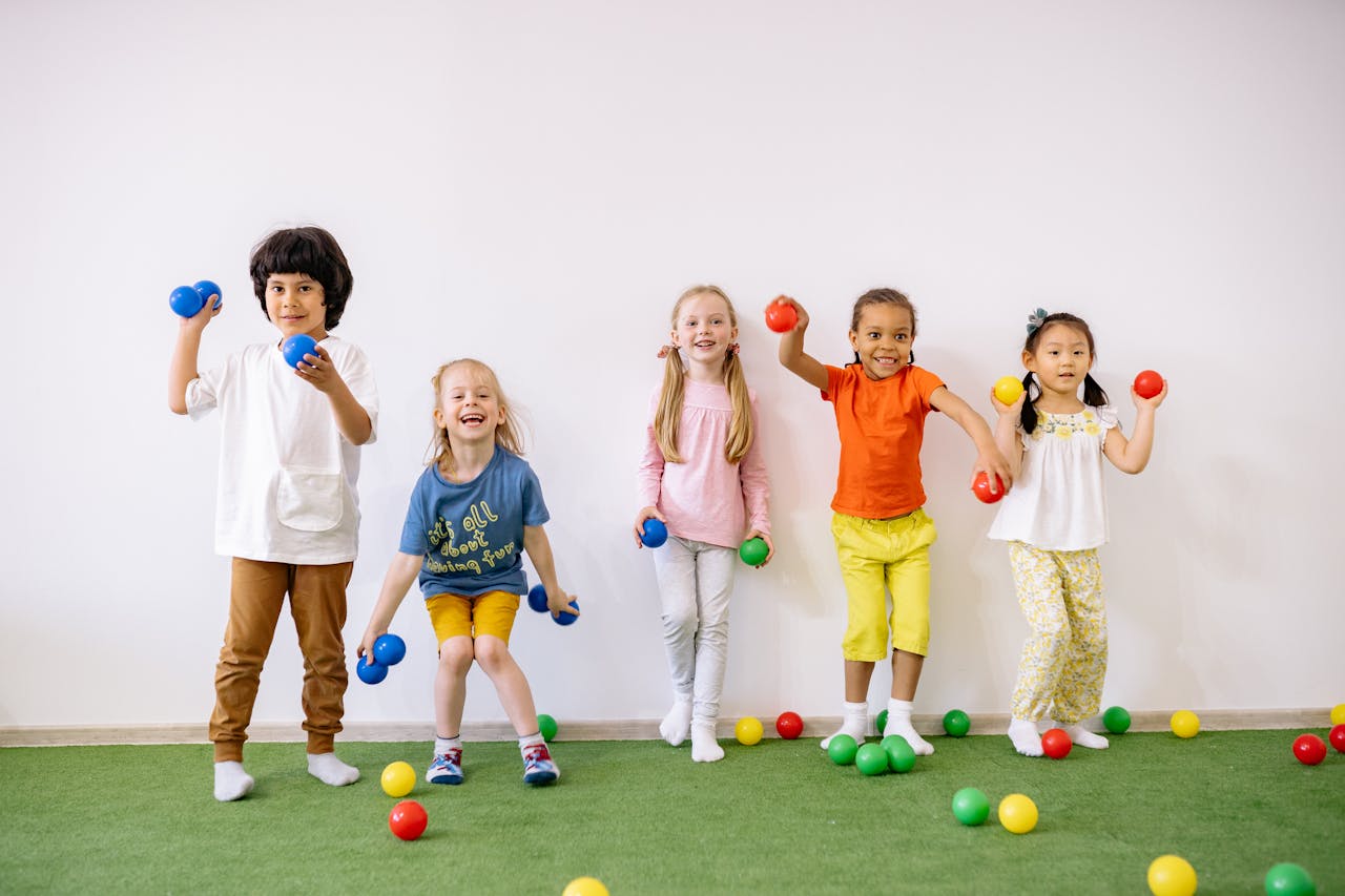 portfolio-06 Happy diverse children playing with colorful balls indoors, showcasing fun and friendship.